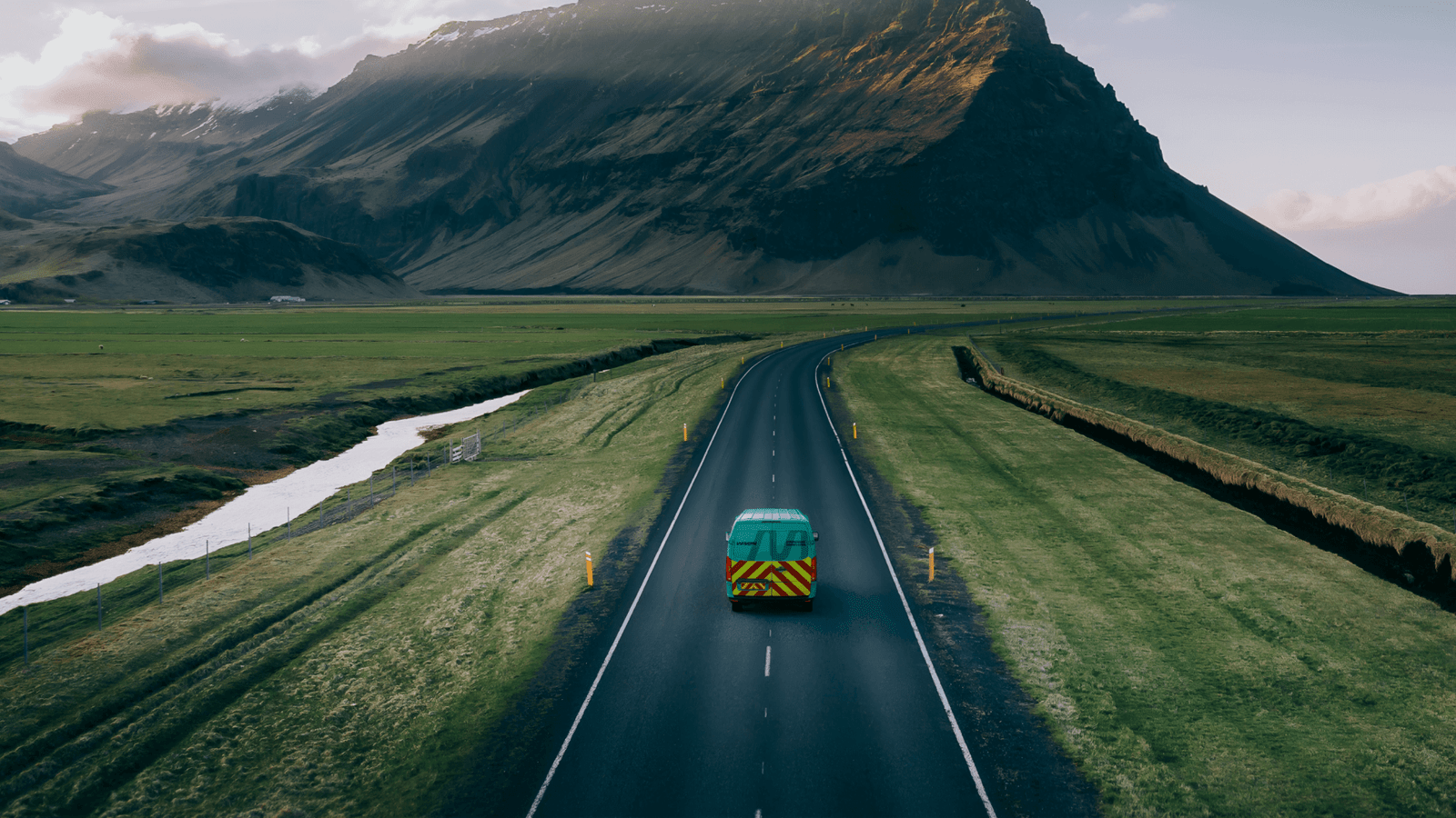 Cyan Branded IMSERV Van on road with a mountain background